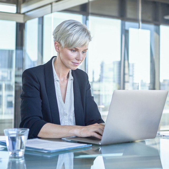 Business-Frau sitzt am Schreibtisch und arbeitet am Laptop  