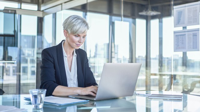 Business-Frau sitzt am Schreibtisch und arbeitet am Laptop  