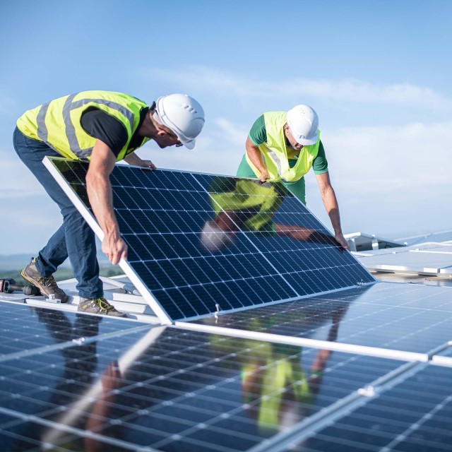 Zwei Ingenieure installieren Sonnenkollektoren auf einem Dach