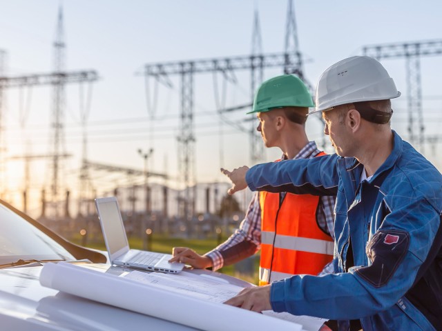Two contruction worker in front of power poles