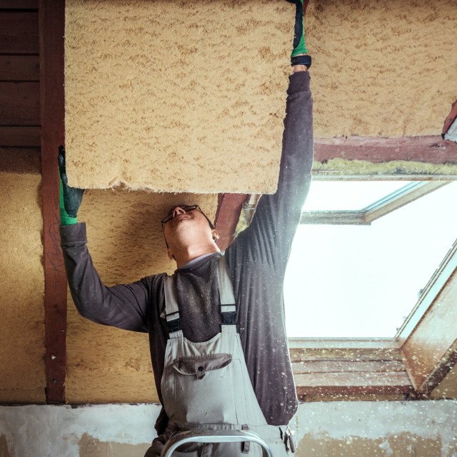 Handwerker baut Dämmung ans Dach