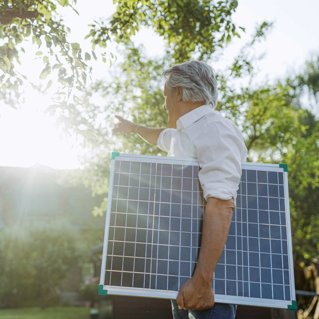 Ein Mann trägt eine Panel einer Solaranlage