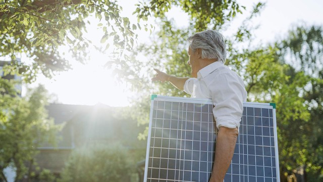 Ein Mann trägt eine Panel einer Solaranlage