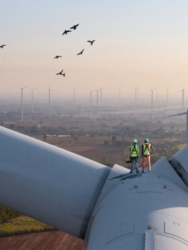 Zwei Ingenieure auf einer Windkraftanlage mit Blick über die Landschaft