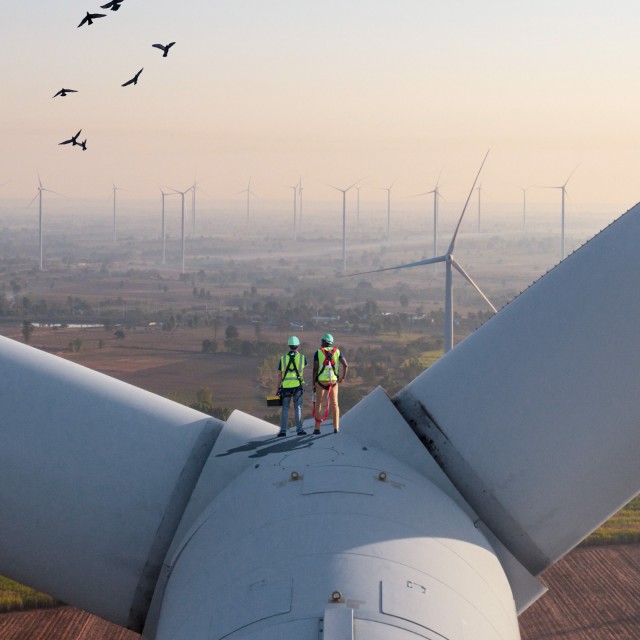 Zwei Ingenieure auf einer Windkraftanlage mit Blick über die Landschaft