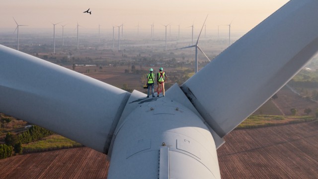 Zwei Ingenieure auf einer Windkraftanlage mit Blick über die Landschaft