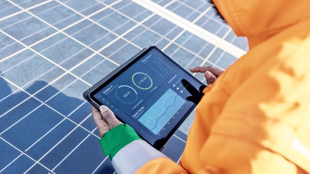 Feldtechniker führt Diagnosetests auf einem digitalen Tablet im Solarpark durch