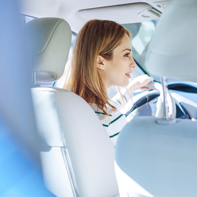 Frau sitzt im Auto hinter Lenkrad