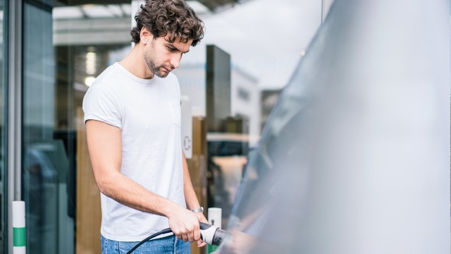 Mann lädt Elektrofahrzeug an Ladestation 