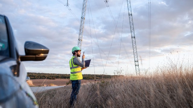 lngenieur steht vor Stromleitung auf dem Feld