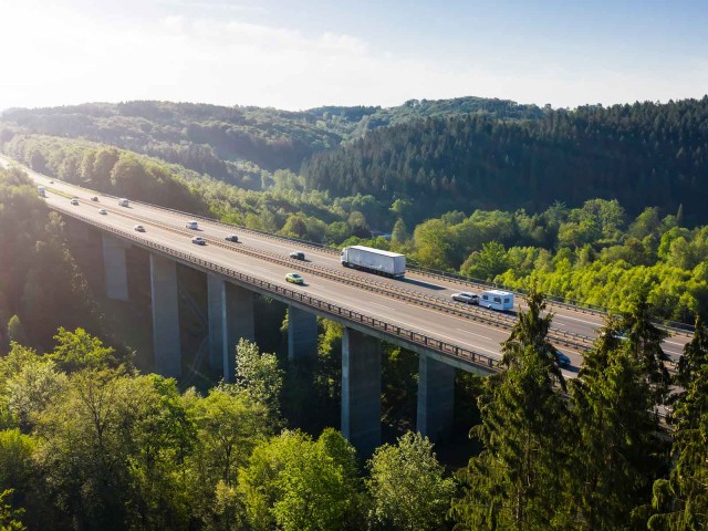 Autobahnbrücke über einem Tal, im Hintergrund Natur und blauer Himmel