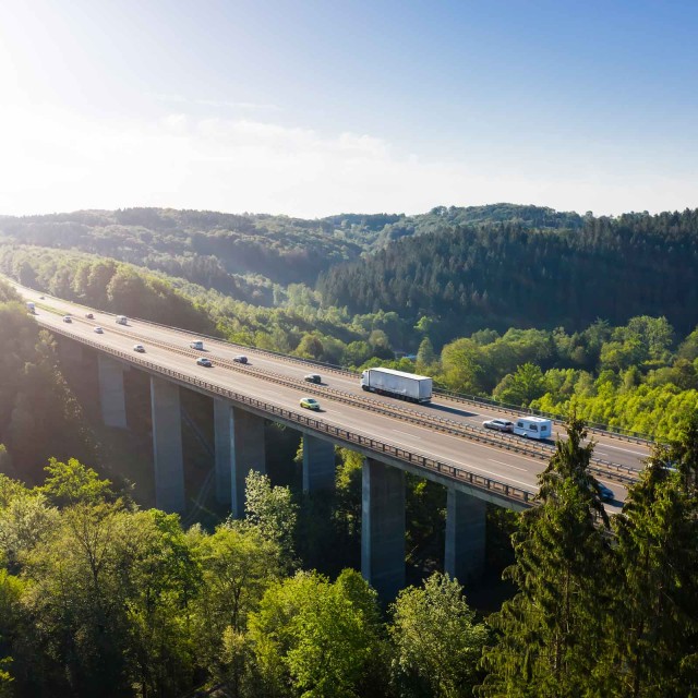 Autobahnbrücke über einem Tal, im Hintergrund Natur und blauer Himmel