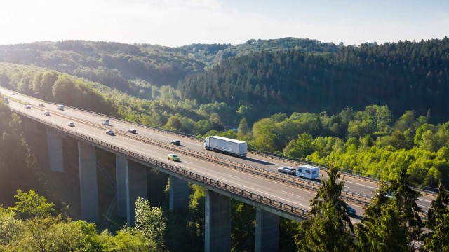 Autobahnbrücke über einem Tal, im Hintergrund Natur und blauer Himmel