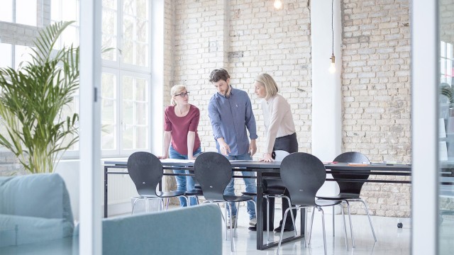 Drei junge Menschen sichten Unterlagen auf einem Tisch