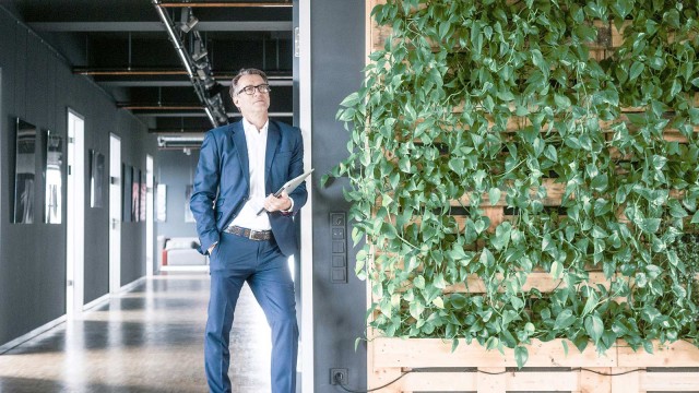 Mann vor Büroflucht neben begrünter Wand 