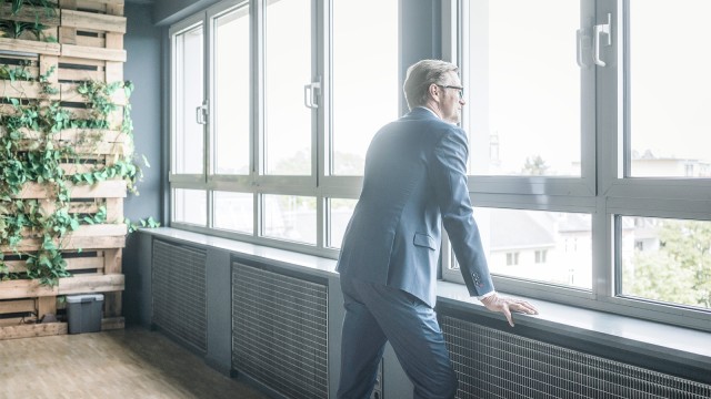 Man in front of green wall looks out the window 