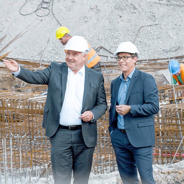 Zwei Männer mit Helm auf einer Baustelle