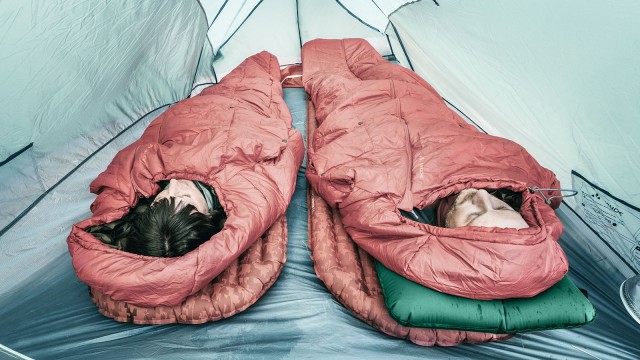 Zwei Menschen im Schlafsack liegen in einem Zelt 