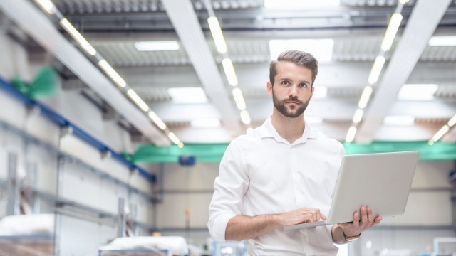 Potrait eines jungen Ingenierus mit Laptop in der Maschinenfabrik