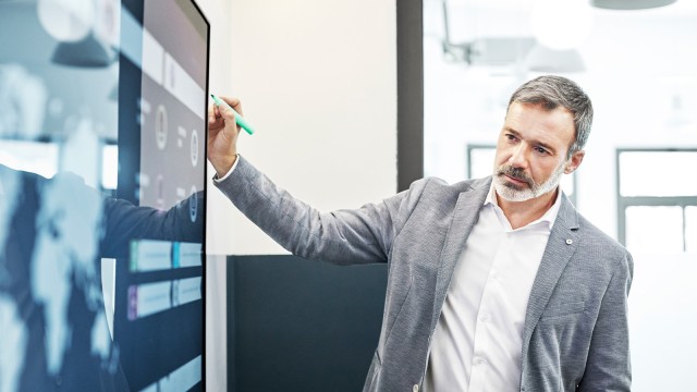 Geschäftsmann mit Stift betrachtet Monitor