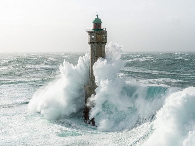 Große Welle, die auf einen Leuchtturm trifft 