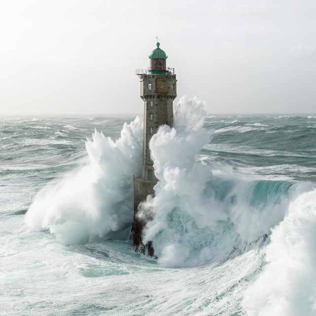 Große Welle, die auf einen Leuchtturm trifft 