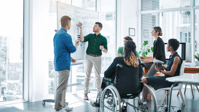 Diverses Team steht zusammen um Flipchart