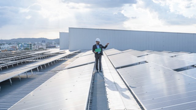 Mann steht auf Dach mit Photovoltaikanlage