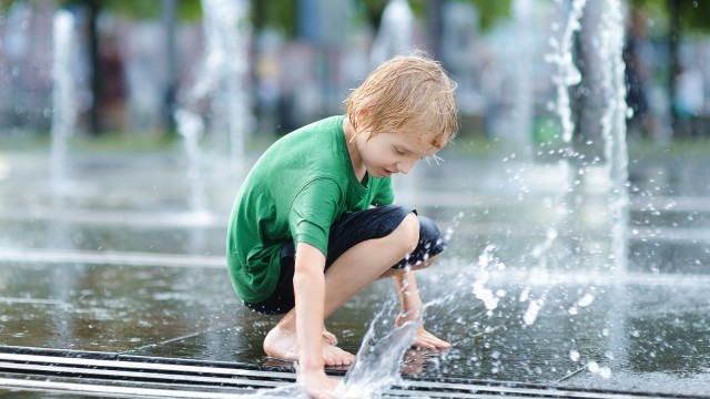 Kind spielt am Brunnen mit Wasser