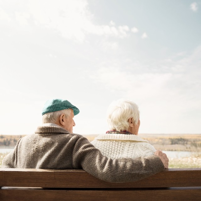 Seniorenpaar auf der Bank sitzend mit Blick auf den sonnigen Herbstblick 