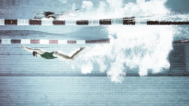 Schwimmerin springt in einen Pool, Unterwasseraufnahme